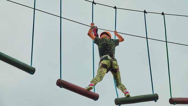 Girl climbing in adventure park is place which can contain wide variety of elements, such as rope climbing exercises, obstacle courses and zip-lines.