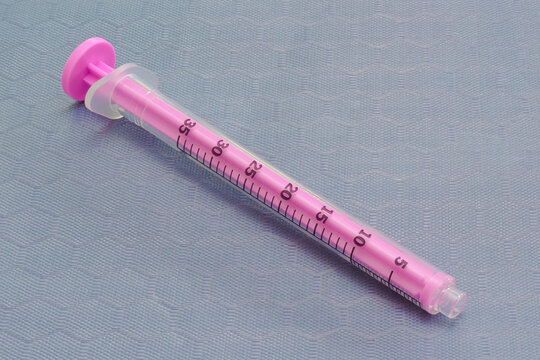 Empty medical syringe on a clinical gray surface.