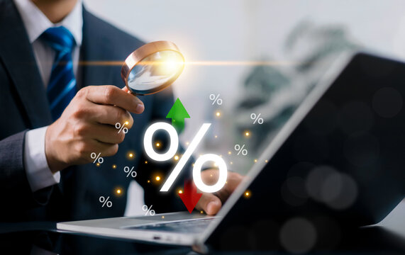 Businessman looking through magnifying glass at digital percentage signs with up and down arrows. Concept of interest rate analysis, financial market trends, economic inflation, investment strategy.