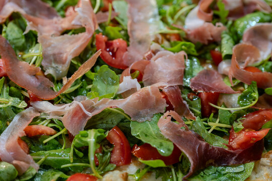 Homemade white pizza with arugula, prosciutto, and cherry tomatoes