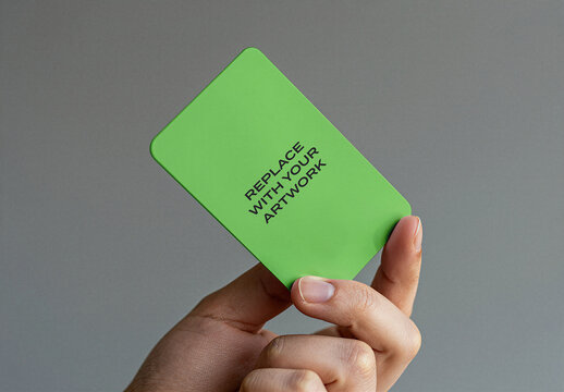 Business card mockup held in hand against neutral gray background, realistic stationery presentation with placeholder text for artwork, vertical orientation, flat close-up view
