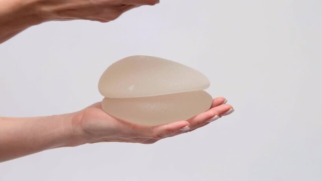 A person demonstrating two stacked breast implants, plastic surgery choices, medical consultation, healthcare marketing, esthetic medicine.