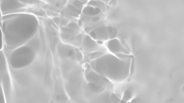 Close-up view of black and white rippling water surface with abstract reflections and moving light patterns. Gray overlay effect for video mockup. High quality 4k footage