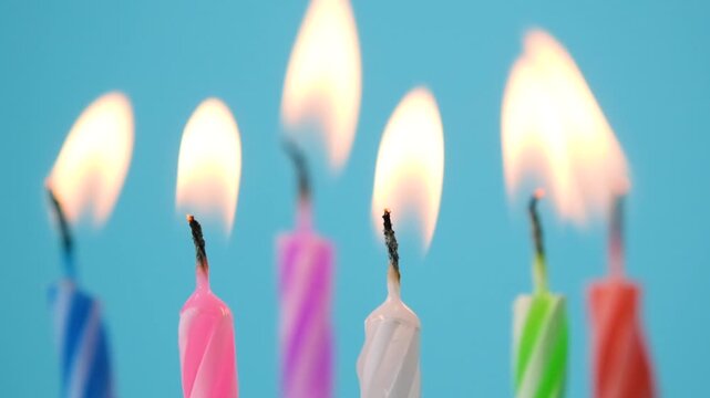 Birthday candles burning and extinguishing against a blue background with glowing flames and rising smoke, a celebration concept showing festive candles before and after blowing out the fire.