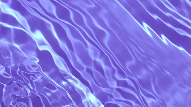 Abstract purple swimming pool water surface with moving ripples and shimmering light reflections. Slow motion video