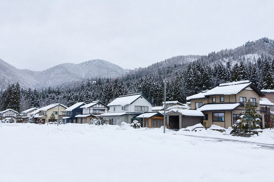 Snow covered mountain village beneath forested winter slopes