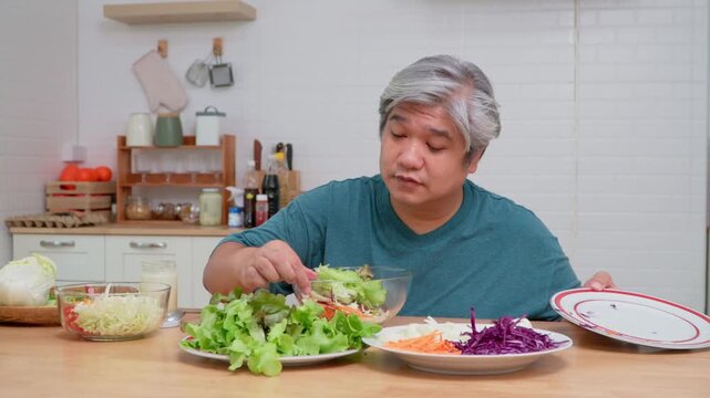 Asian elderly man eating fresh salad in kitchen, symbolizing healthy food, wellness, nutrition, and lifestyle concept in cheerful indoor environment with vegetables, daylight, and positive atmosphere