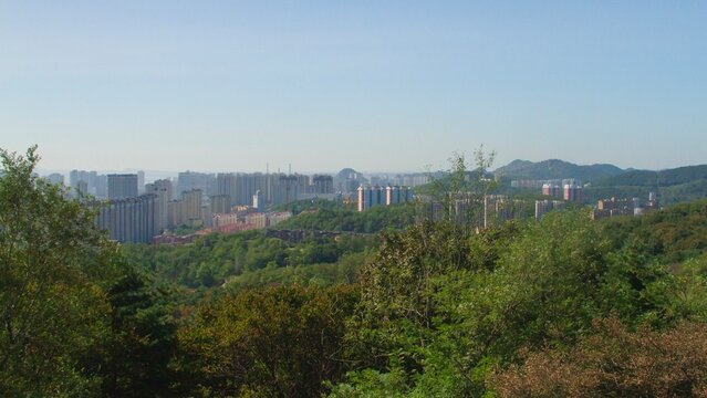 A elevated panoramic view looking down over the high-rise residential buildings and distant rolling hills of the Siping cityscape, China.