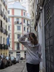 Fototapeta premium Rear view of a woman in a beige ruffled blouse walking along a narrow street in Madrid Spain
