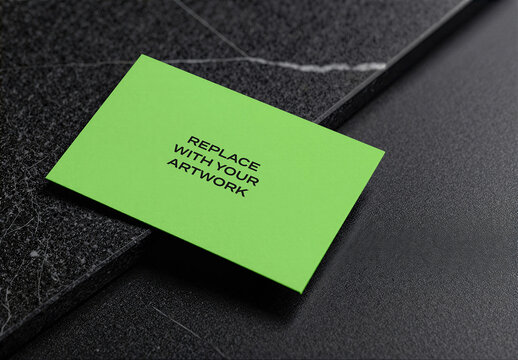 Business card mockup on textured black marble surface with diagonal placement, realistic stationery branding presentation, template for graphic design, print, and advertising display