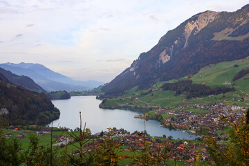 Fototapeta premium Swiss Alpine Village by Turquoise Lake Surrounded by Mountains in Switzerland