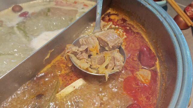 Close up of ladle scooping cooked lamb meat from boiling hot pot broth in Ulanqab, Inner Mongolia, China
