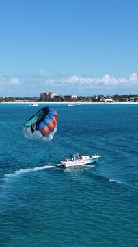 Parasailing In Providenciales Turks And Caicos United Kingdom. Thrilling Adventure With Speedboat Paragliding In Turquoise Ocean. Bay Water Landscape. Seaside Beach. Providenciales Turks and Caicos.