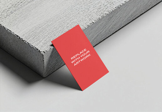 Business card mockup leaning against a concrete block on light gray surface, vertical presentation with clean lines and modern industrial aesthetic, Template, realistic stationery display flat
