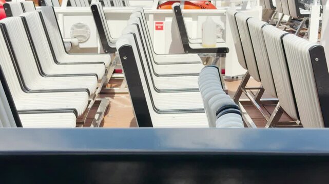 White boat chairs line up on an open vessel deck in Saint Petersburg. The empty seats wait under bright sunlight. The quiet atmosphere feels peaceful and inviting.