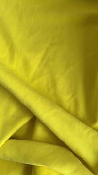 Yellow fabric background with soft folds and shadow movement