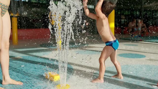 Happy Young Boy Laughing and Playing at Splash Pad Fountain