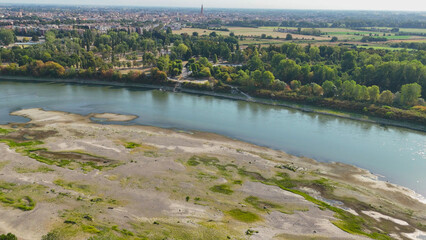 Obraz premium Po River experiencing critical low water levels during 2026 heatwave drought, revealing extensive sand banks near Cremona, symbolizing climate change and water crisis