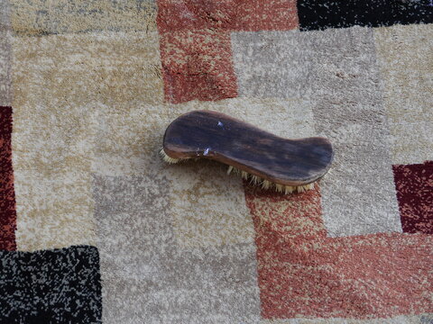 Wooden brush is laying on a carpet