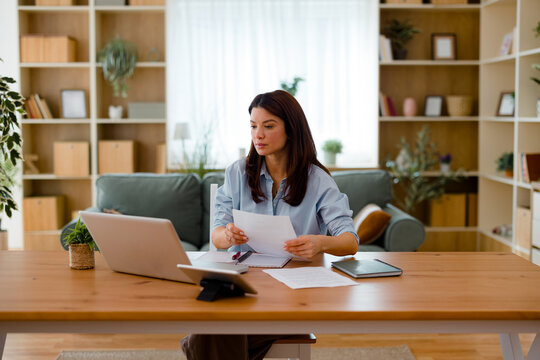 Woman working remotely from home office analyzing documents