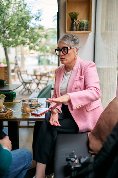 Woman in pink jacket talking in cafe