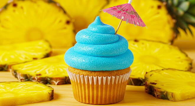 Cupcake with Blue Frosting and Cocktail Umbrella Surrounded by Pineapple Slices