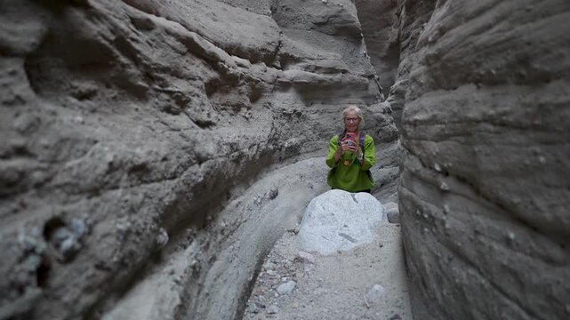 Senior woman hikes through a slot canyon in Anza Borego State Park. She smiles and enjoys nature while exploring the desert area.