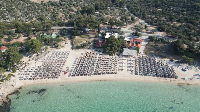 Aerial pull back shot of Psili Amos beach showing crystal clear sea and surrounding green hills, southern Thassos, Greece.
