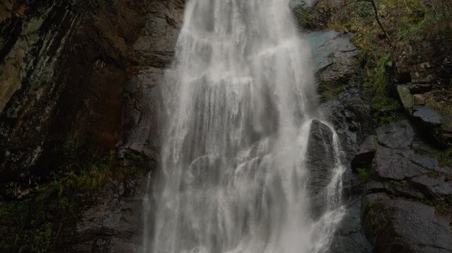 Scenic waterfall stream pouring over dark wet rocks.