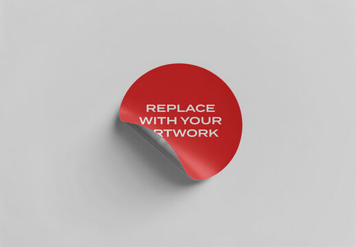 Circular sticker mockup with peelable corner on neutral gray surface for branding and graphic design presentation, template product packaging promotional artwork display