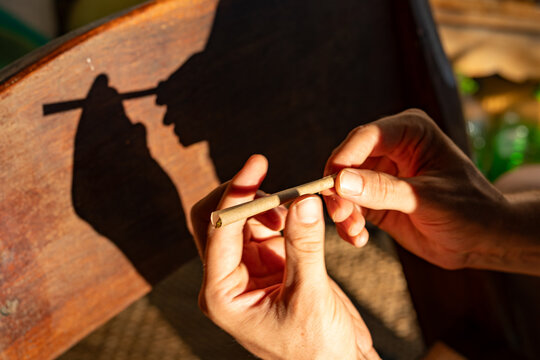 Hands Rolling Cannabis Joint with Silhouette Shadow on Wood