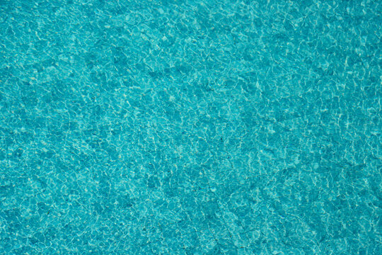 Vibrant blue water surface with shimmering reflections and ripples under sunlight