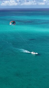 Parasailing In Providenciales Turks And Caicos United Kingdom. Thrilling Adventure With Speedboat Paragliding In Turquoise Ocean. Landmark Coast. Bay Water Landscape. Providenciales Turks and Caicos.