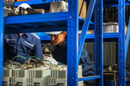 Industrial engineers inspecting electronic machinery, servo drives spare parts storehouse. Concept of second hand component recycling, technology hardware audit, maintenance, technical operations.