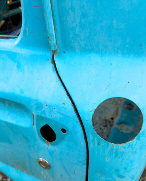 Bright blue dilapidated old pickup truck with gas cap and handle missing
