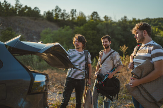 Friends packing camping gear into car trunk for road trip