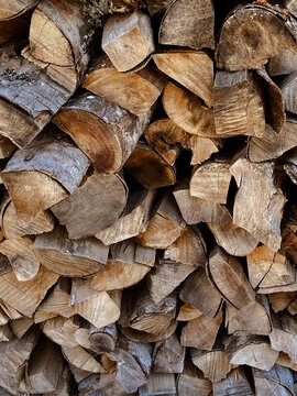 Cut logs showcasing wood with grain and a rough, weathered texture, providing a rustic background for themes of nature, forestry, and energy sources.