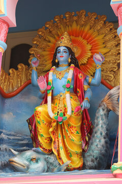 Colorful painted cement wall relief of Hindu god Vishnu stepping on the giant Matsya fish avatar.
