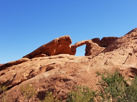 Natural sandstone arch in the Nevada desert under blue sky