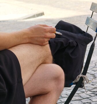 Close up of young man hand holding burning cigarette outdoors