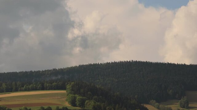 Time-lapse 4K montrant le d&eacute;placement rapide de nuages au-dessus d'une for&ecirc;t du Val-de-Travers, dans le canton de Neuch&acirc;tel, en Suisse. La succession des nuages et les variations de lumi&egrave;re cr&eacute;ent une