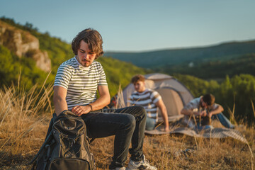 Fototapeta premium Young man packing backpack during camping trip with friends