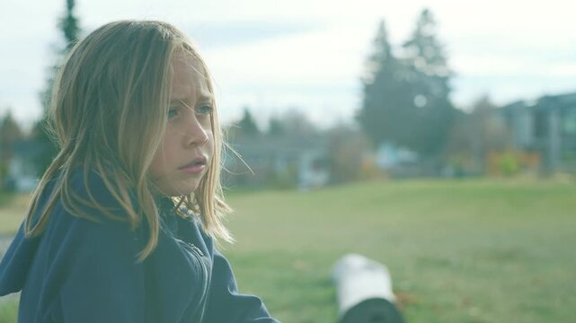 Pensive boy portrait with wind blowing through his hair at a park