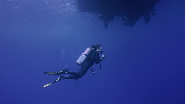  Female scuba diver under boat at safety stop.