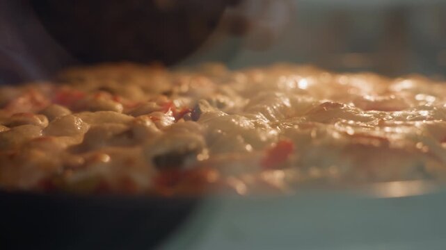 Low-angle close-up of thick tomato stew simmering in shallow pan inside oven, showing rolling bubbles, rising steam, small splashes, glossy surface, and rich warm color, with simmering, bubbling