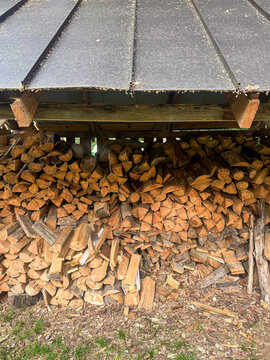 View of a neatly stacked woodpile under a wooden shed roof in Engure, Tukums Municipality, Latvia.