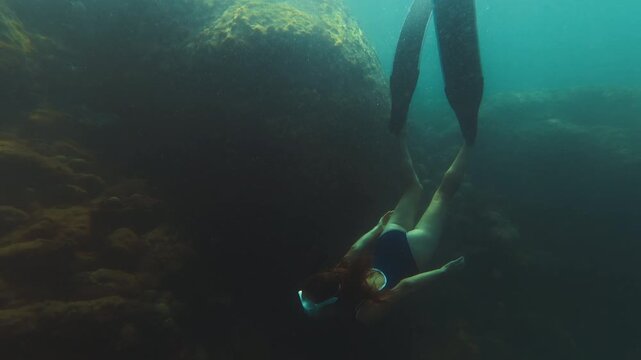 Young slim woman swims underwater, freediving and snorkeling in the sea near the coral reef near the island of Ilha Grande in Brazil