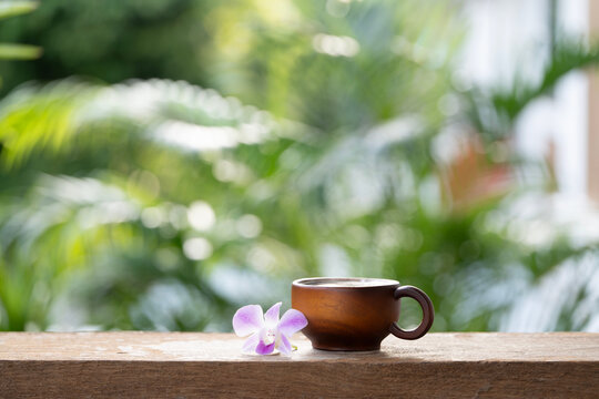 Rustic wooden cup and purple orchid flower with nature green background