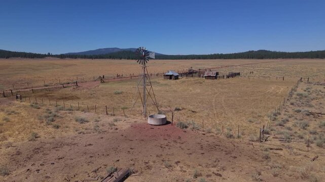 Aerial orbit revealing working windmill and abandoned ranch structures, Lassen County, California.