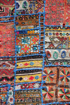 Abstract background of a traditional Indian patchwork tapestry with colorful handmade embroidery and mirror work.